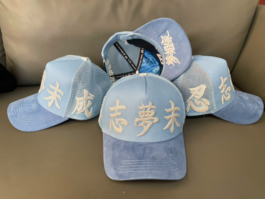 Light blue suede trucker cap with gold embroidered Chinese characters, shown as a set of four.
