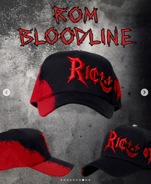 Black cap with red blood splatter print and a red embroidered Rico Muerto Bloodline logo.