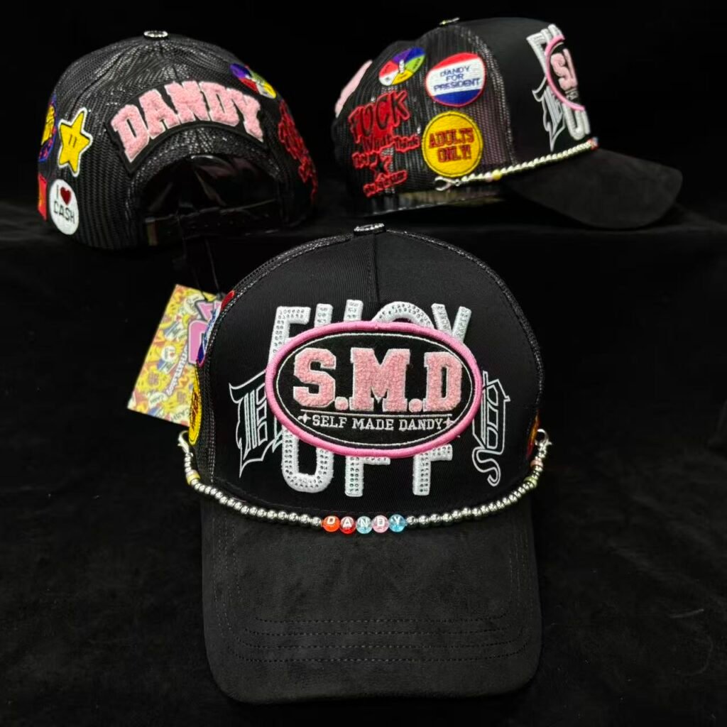 Black trucker cap with S.M.D. Self Made Dandy embroidered in pink, chenille patches and a bead chain.